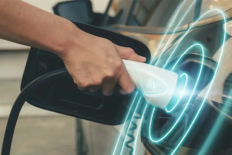 Hand connecting EV charger to car with glowing digital effect, symbolizing hotel EV charging stations.