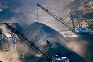 Large mining site with electric mining trucks and cranes operating among piles of minerals, representing battery-swap technology for heavy-duty EVs.