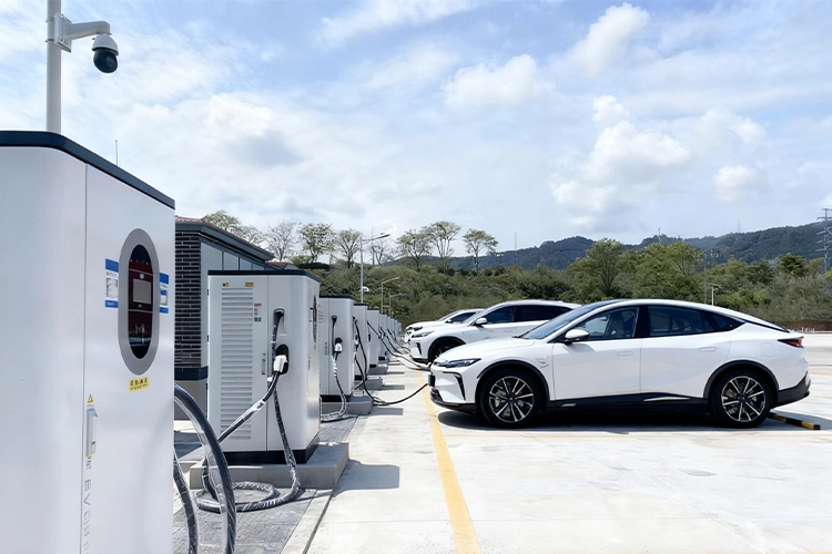 Modern EV charging station with multiple DC fast chargers and electric vehicles charging outdoors.