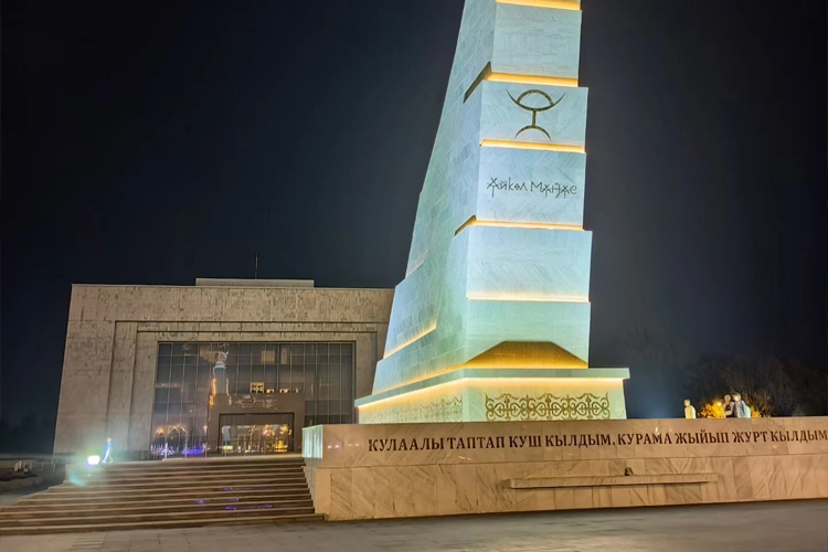 Night view of a monument and government building in Kyrgyzstan, related to EV charging station market visit and clean energy cooperation.